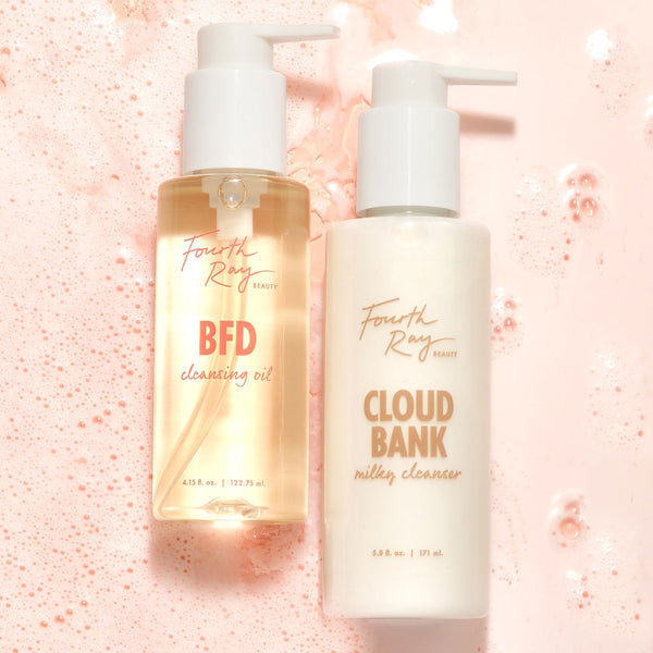 ColourPop Cleansing Duo Comfort set showing Fourth Ray Beauty BFD Cleansing Oil (4.15 fl oz) and Cloud Bank Milky Cleanser (5.8 fl oz) standing side by side with white pumps on a pink foamy backdrop, highlighting a gentle double-cleanse routine.