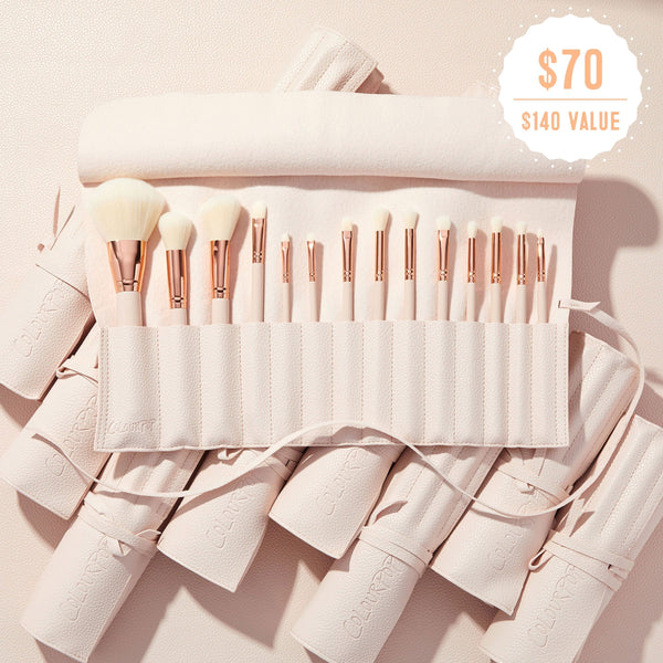 ColourPop Doin’ the Most brushes fanned in a soft pink travel roll, rose‑gold ferrules and white bristles on display, promoting the ColourPop Shadow Palette & Brush Set with $70 ($140 value) badge against a blush textured background.