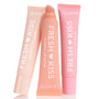 Pretty in Pastels ColourPop Glossy Lip Balm Trio showcases three Fresh Kiss glossy lip balms - soft pink, peach, and blush - with the center tube uncapped to show a slanted applicator, arranged upright on a white background.