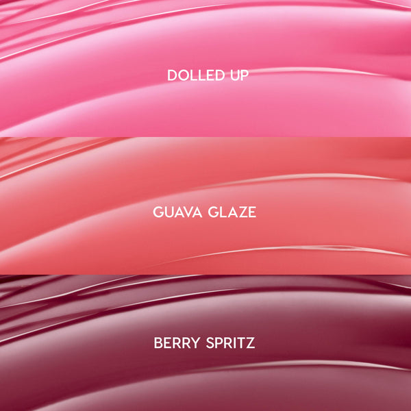ColourPop So Juicy Plumping Gloss Balm with Peptides swatches showing She’s So Juicy shades: Dolled Up (bright pink), Guava Glaze (coral peach), and Berry Spritz (deep berry), displayed as glossy curved stripes in a close-up bundle layout.
