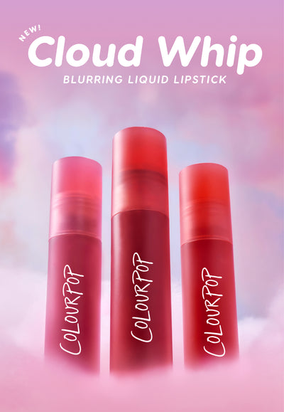 Three red ColourPop Cloud Whip blurring liquid lipstick tubes stand upright in fluffy pink clouds against a dreamy pastel sky, highlighting the soft-focus, whipped formula and new makeup launch for US beauty shoppers.