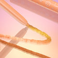 Movie Star ColourPop Chrome Crème Gel Liner drawing a smooth, glittering gold-to-peach chrome line on a glossy surface; peach twist-up pencil with star and smiley icons, set against a pink-to-gold gradient background.
