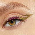 Chrome winged eyeliner creates a sharp elongated flick across a close-up eye, shifting olive-gold with magenta-lime along the lash line, showcasing ColourPop Chrome Crème Gel Liner, shade Chrome Hearted, on natural lashes and a groomed brow.