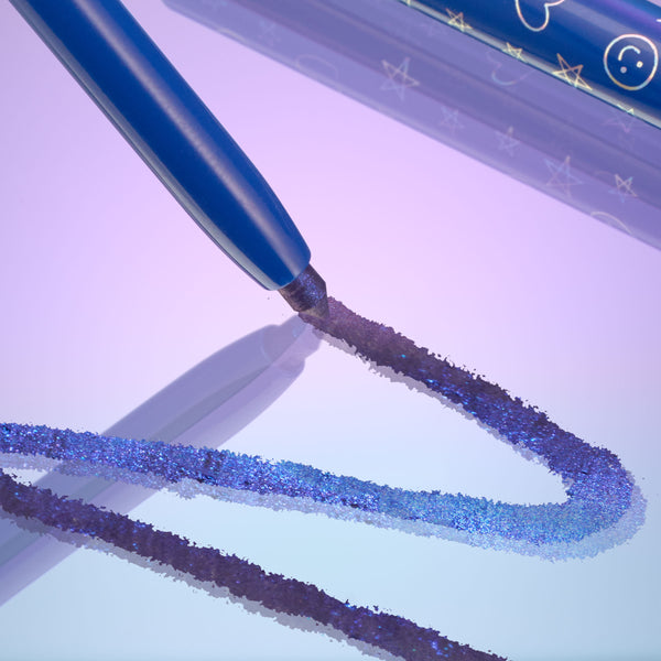 ColourPop Chrome Crème Gel Liner Ventura Blvd draws a shimmering blue‑purple chrome line on a glossy surface, the blue pencil barrel with celestial icons shown close up against a pastel lilac gradient studio backdrop.