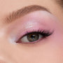 Shimmering pastel pink‑lilac eyeshadow blends across a close-up eyelid with fluttery lashes, showcasing the color payoff of the In A Trance shadow palette, a ColourPop Shadow Palette, perfect for soft, iridescent looks.