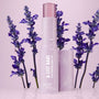 A-List Babe Serum Stick standing uncapped with dewy droplets on a pastel lavender tube, framed by purple lavender sprigs on a glossy pink surface; ColourPop Serum Stick by Fourth Ray Beauty for easy swipe-on face serum.