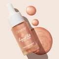 ColourPop Liquid Highlighter Venice Blvd bottle with white dropper rests diagonally, spilling pearly rose-gold glow drops and a swirled swatch on a light beige background, showcasing Liquid Lite Glow Drops' radiant, buildable finish.