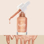 Venice Blvd ColourPop Liquid Highlighter shows an open glass bottle as a white-capped dropper drips shimmery rose-gold glow drops, the “liquid lite glow drops” label visible, with metallic swatches pooling along the bottom on a nude backdrop.