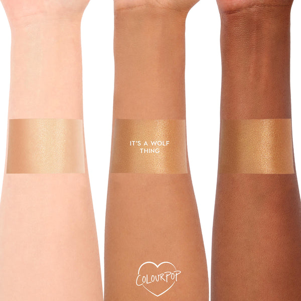 ColourPop SOL Glow Oil It’s a Wolf Thing swatched in wide bands across three arms with light, medium, and deep skin tones, revealing a warm golden shimmer and glossy finish; ColourPop heart logo at the bottom.