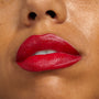 Bold, slightly parted lips wear Va Va Voom, a ColourPop Lippie Stix + Pencil Set, showcasing vibrant classic red color with a creamy satin finish and pencil-defined edges in a clean studio close-up.