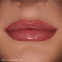 Glossy lips wearing ColourPop So Juicy Plumping Gloss Stick in Pinky Who, delivering sheer rosy pink shine that visibly plumps and smooths the mouth, shown in a tight close-up on natural skin as a beauty swatch.