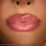 Close-up lips wearing ColourPop So Juicy Plumping Gloss Stick, shade Pinky Who, showing a cushy, plumped look with sheer medium‑pink, high‑shine finish under studio lighting.