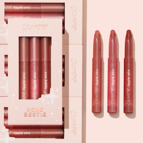XOXO Bestie ColourPop Lippie Stix trio swiveled up and lined beside the matching pink gift box with star accents, showing three rosy mauve nude shades in sleek twist-up tubes, a limited-edition set ideal for everyday lip color.