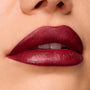 Slow Burn ColourPop Lux Lipstick draping full lips in a deep wine‑burgundy satin finish, showing smooth, precise edges and creamy payoff in a tight macro beauty close‑up.