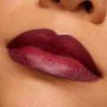 Lips wearing Slow Burn, a deep burgundy ColourPop Lux Lipstick, showing smooth full-coverage satin-matte color with crisp edges in a macro studio close-up, highlighting rich pigment and creamy texture.