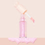 Pink Pony ColourPop Liquid Highlighter drips from a doe-foot applicator, the open clear bottle with cream heart-shaped cap set on a blush background above a glossy iridescent pink swatch.