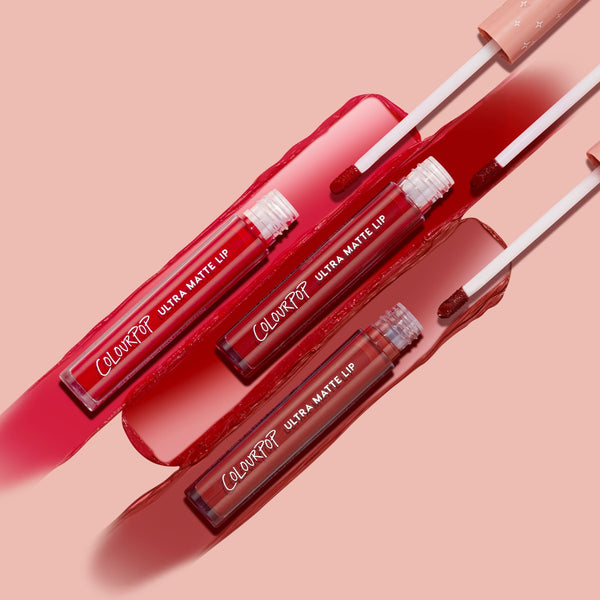 Major Hottie ColourPop Ultra Matte Lip tubes with doe-foot applicators sweeping three red swatches - bright cherry, classic crimson, and deep brick - across a blush-pink backdrop, highlighting long-wear ultra matte liquid lipstick.