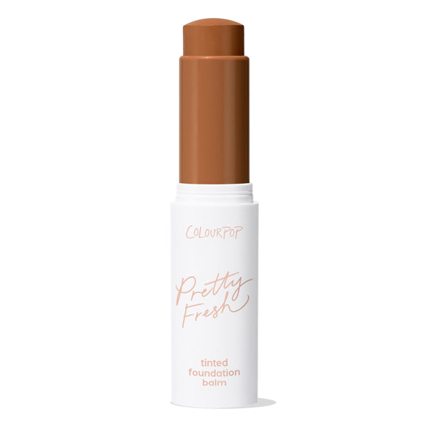 ColourPop Pretty Fresh Tinted Foundation Balm, shade Dark 20, stands uncapped with the twist-up stick exposed in a deep warm brown, housed in a white tube labeled Pretty Fresh against a clean white background.
