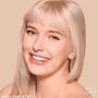 Model wearing ColourPop Pretty Fresh Tinted Foundation Balm, shade Fair 3, smiling in a close-up; skin appears even, dewy, and natural with lightweight, buildable coverage against a warm beige background.