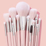 Smoke 'N Roses Brush Roll, a ColourPop Makeup Brush Kit, arranged upright with fluffy pink-and-white bristles and blush pink handles with silver ferrules, featuring powder, blush, shader, and spoolie brushes against a soft pink backdrop.