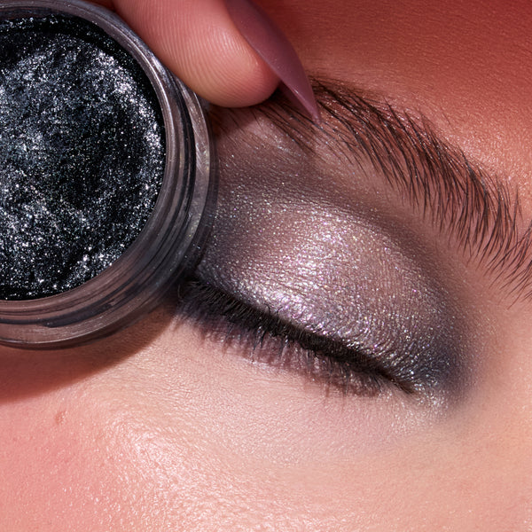 Newborn Army Jelly Much Shadow from the Twilight collection pressed near a closed eye, showing metallic silver-lilac shimmer and deep charcoal sparkle blended across the eyelid for an intense, wet-look eyeshadow finish.