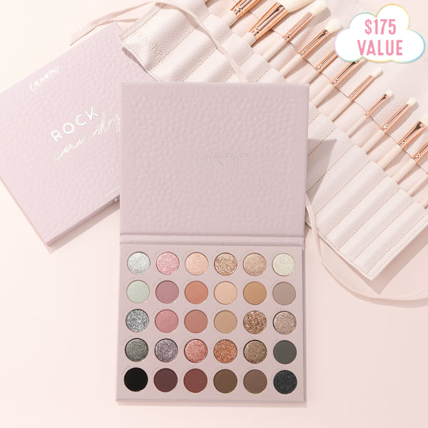 Major Eye Candy shadow palette and brush set by ColourPop displaying 30 neutral and glitter shades in an open lilac case, with rose-gold brushes in a white roll beside it, flat lay on a soft pink surface with a $175 value badge.