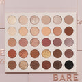 Bare Necessities ColourPop Shadow Palette showcasing 30 neutral matte and shimmer shades in a 6x5 grid - ivory, taupe, mauve, bronze, gold, deep brown, and black - laying open on blush-pink packaging with BARE lettering, ideal for everyday looks.