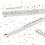 Soft Brown ColourPop Freckle Pen uncapped, felt-tip applicator ready to dot natural-looking freckles, shown with polka-dot cap and matching box on a white background speckled with brown spots; 1.0 ml makeup pen for faux freckles.