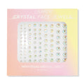 ColourPop Crystal Face Jewels Individual sheet displaying 81 iridescent round adhesive crystals in varied sizes arranged in neat rows, set in pastel pink-to-yellow ombré packaging for customizable face accents.