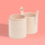 Small Stash Cup by ColourPop standing open - two beige faux‑leather cylindrical holders with snap tabs and stitching - for storing makeup brushes, tools, and accessories, displayed on a peach background.
