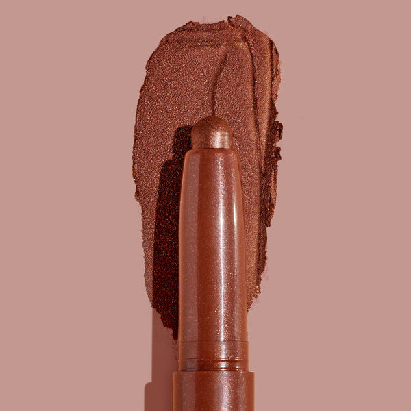 ColourPop Shadow Stix So Into U glides a metallic rose‑bronze swipe across a blush‑pink backdrop, showcasing the creamy twist‑up eyeshadow stick’s high shimmer, smooth payoff, and rounded precision tip.