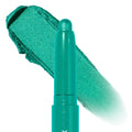 Surf Sesh ColourPop Shadow Stix eyeshadow crayon glides a metallic teal‑green swatch, the creamy stick shown uncapped with a rounded tip in a macro close‑up on a white background.