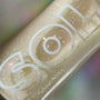 SOL-labeled bottle sparkles as fine rainbow glitter swirls in a golden base; ColourPop SOL Shimmering Dry Oil, Rainbow Glow, shown in a tight macro against a soft iridescent backdrop for a luminous body sheen.