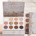 11:11 ColourPop Shadow Palette opens to 12 neutral and rosy tones - matte, shimmer, and pressed glitter - with star and wing embossing; displayed in brick-and-gold celestial packaging with stacked palettes beside it in soft studio light.