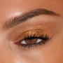 Brown eye wears shimmering copper-gold lids with defined lashes, showcasing the 11:11 ColourPop Shadow Palette shadow's rich bronze sparkle and smooth blend in a close-up beauty shot, perfect for soft neutral glam.