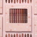 Truth or Bare Lippie Pencil kit by ColourPop displayed in a pink windowed box, 10 nude lip liner shades from peach to deep brown standing upright, surrounded by matching pencils and boxes on a pastel pink background with kiss and star icons.