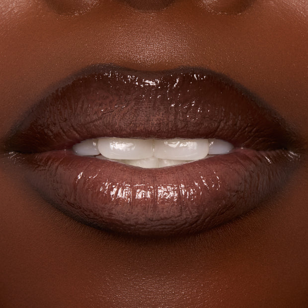 Lips wearing ColourPop Ultra Glossy Lip in Coffee Break, showing a rich coffee-brown, high-shine finish in an extreme close-up of a slightly parted mouth, highlighting smooth, glassy coverage and a plush, glossy nude look.
