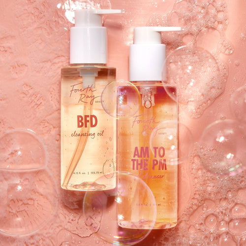 Come Clean Cleansing Duo by Fourth Ray Beauty - BFD Cleansing Oil (4.15 fl oz) and AM to the PM Cleanser (5.8 fl oz) in clear pump bottles - standing with airy bubbles on a glossy pink surface; ColourPop Face Cleanser set for double cleansing.
