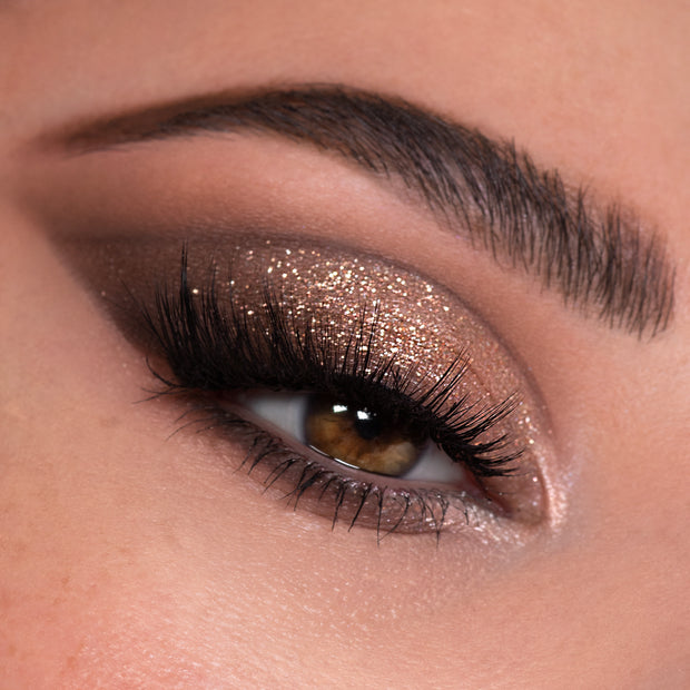 Shimmering bronze glitter eyeshadow on a brown eye, created with Rock Candy Shadow Palette, a ColourPop Shadow Palette; soft taupe crease, bright inner-corner highlight, full lashes, and defined brow.