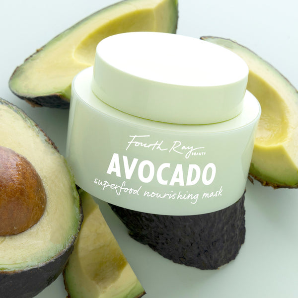 Mint-green jar of Fourth Ray Beauty Avocado Superfood Mask face mask rests among sliced avocados on a light surface, highlighting nourishing hydration and sleek packaging; a ColourPop Face Mask for glow-boosting skincare.