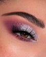 Glam eye displays sparkly silver lid fading into mauve‑purple crease with long, voluminous lashes, created using the ColourPop Shadow Palette Rock Candy; close-up under a groomed brow to show pigment, shimmer, and seamless blend.