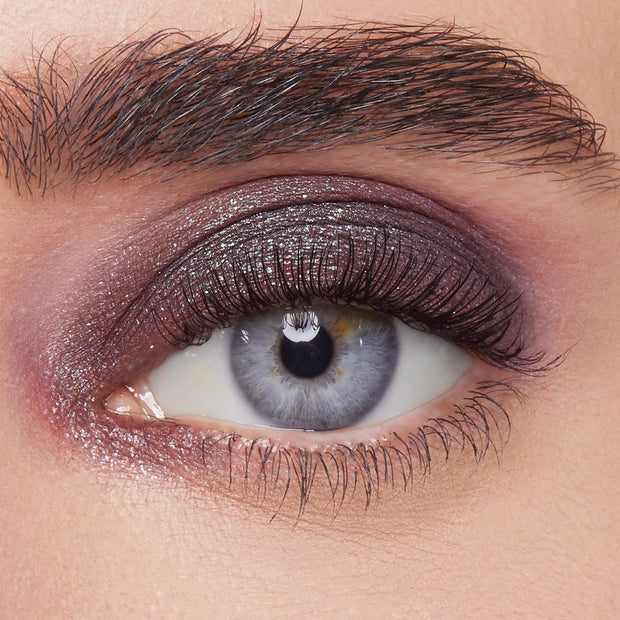 Shimmery plum eyeshadow sweeps across the eyelid, showcasing ColourPop Bae Super Shock Shadow on a close-up eye with defined lashes and brow, highlighting metallic sparkle, smooth blend, and rich payoff for a bold evening makeup look.
