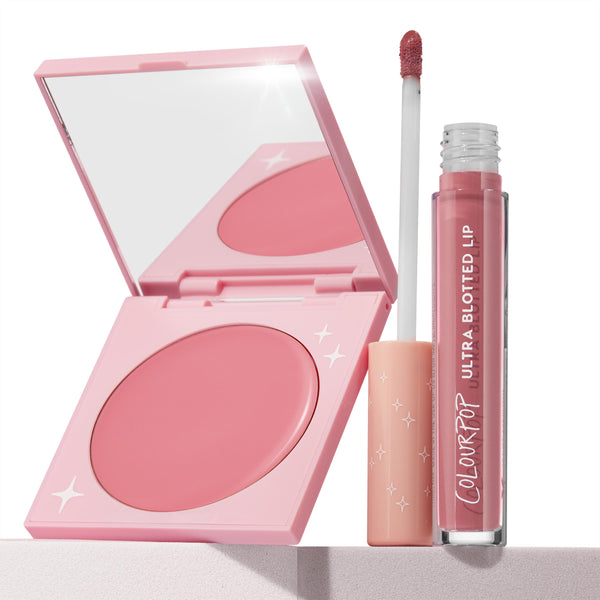 That’s So Rosy ColourPop Cheek & Lip Set showcasing an open pink compact cream blush beside an Ultra Blotted Lip tube with doe-foot applicator, both in rosy mauve tones, styled on a light pedestal against a clean white background with star-accent packaging.