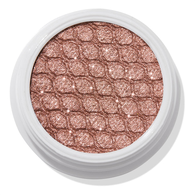 Aster ColourPop Super Shock Shadow sparkles in a close-up of its shimmery rose-gold single eyeshadow pan, embossed with a quilted texture inside a white round pot, studio-lit against a clean white background.