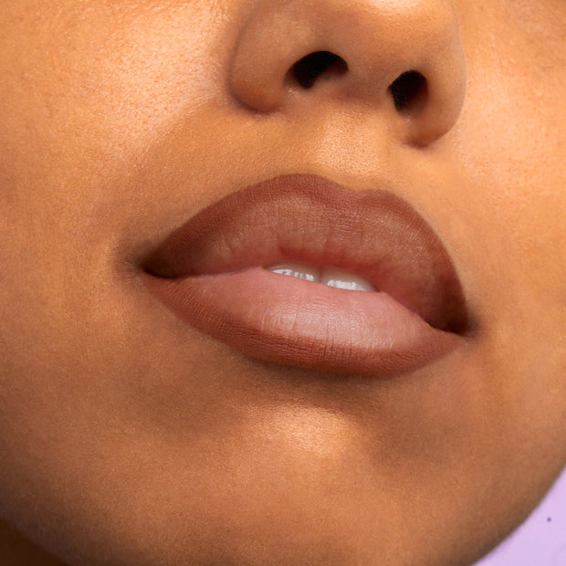 Lips softly lined and slightly filled with ColourPop Truth or Bare Lippie Pencil, a warm nude-brown, crisply defining the cupid’s bow with a smooth matte finish in a tight close-up beauty shot under soft studio lighting.