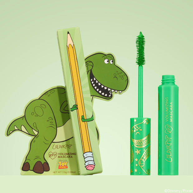 ColourPop BFF Mascara Roar! stands upright with a vivid green brush, shown beside Disney•Pixar Toy Story Rex–themed packaging and a pencil-print box; volumizing neon‑green tube set against a soft mint background.