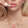 So Juicy lip oil glides onto glossy pink lips with a doe-foot applicator as a gold charm necklace - featuring a pink ColourPop lips pendant and mini So Juicy tube - rests on the neck; Charmed and Juicy, the ColourPop So Juicy Lip Oil and Necklace Set.