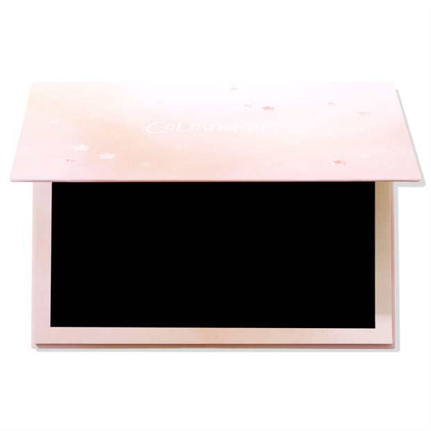 Stars Large Empty Palette lying half-open, revealing a black magnetic interior for single pans, with a blush-pink lid sprinkled with stars and ColourPop logo; ColourPop Empty Palette for building a custom makeup collection.