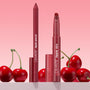 Bichette ColourPop Lippie Pencil and matching Lippie Stix stand upright with caps off, revealing rich cherry-red tips, surrounded by glossy cherries on a pink gradient backdrop, highlighting a creamy, precise liner duo for bold red lips.