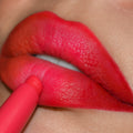 Chi Chi ColourPop Lippie Pencil lining lips, depositing bold coral‑pink, soft‑matte color; extreme close-up shows the pencil’s precision tip defining the cupid’s bow and lower lip for a crisp, saturated outline.